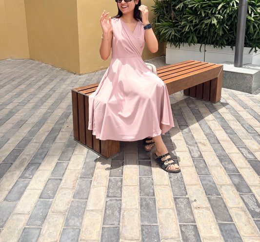Woman in a pink dress sitting on a wooden bench outdoors.