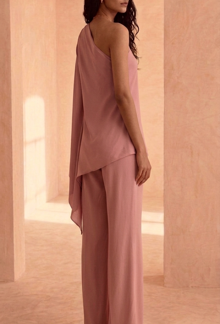 Woman in a pink outfit standing in an archway with a soft, warm color palette.
