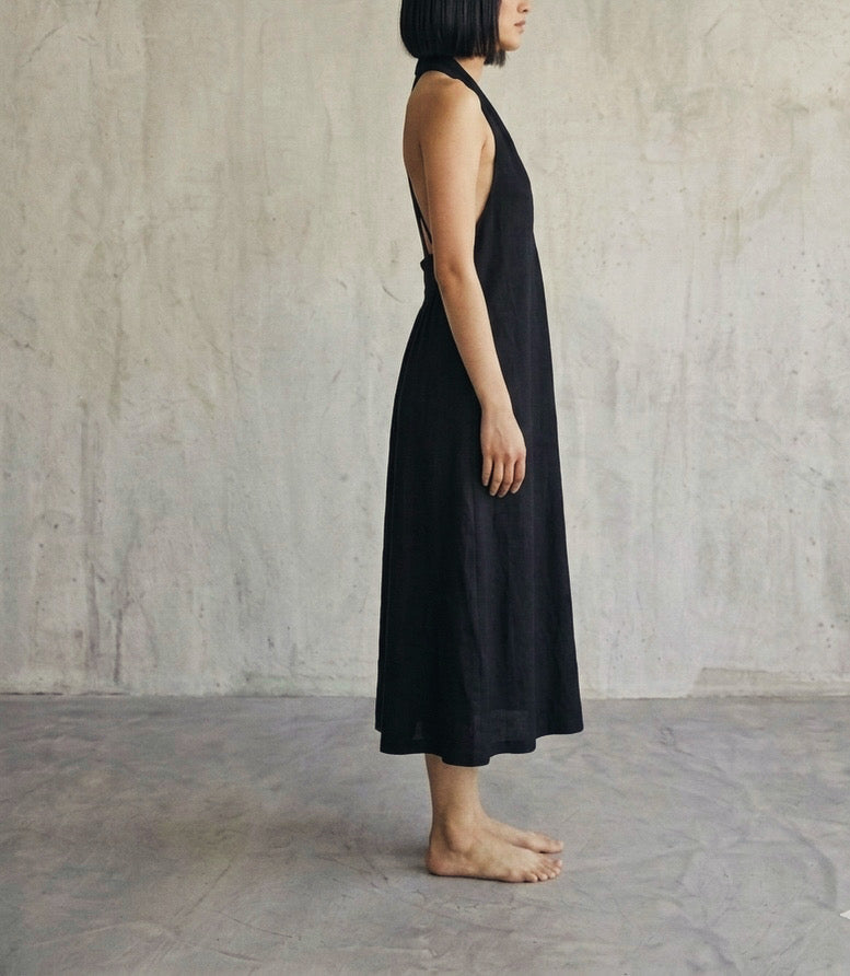 Side view of women’s black sleeveless halter midi dress with flowing relaxed fit silhouette
