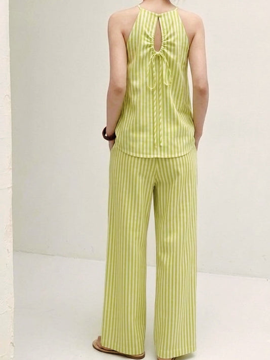 Side view of pistachio green striped matching set with halter neck sleeveless top and loose wide leg trousers.
