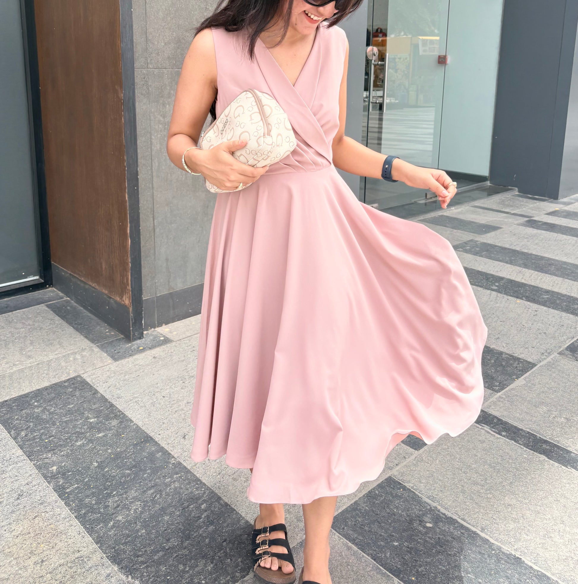 Woman in a pink dress standing on a tiled pavement.